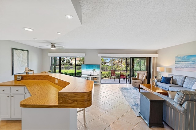 tiled living room featuring ceiling fan and a textured ceiling