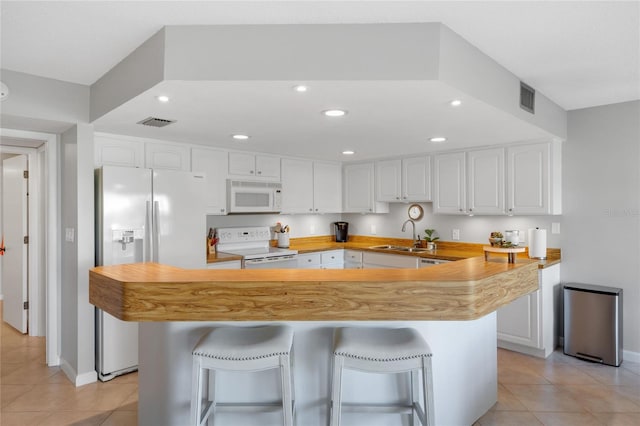 kitchen featuring a breakfast bar, white cabinetry, white appliances, and kitchen peninsula