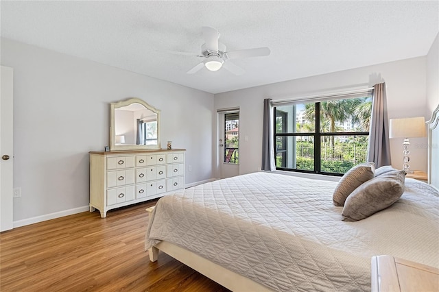 bedroom with ceiling fan, light hardwood / wood-style floors, and a textured ceiling