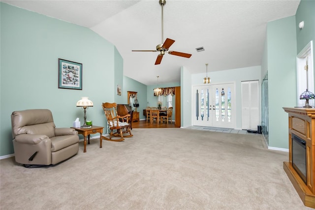 living area featuring ceiling fan with notable chandelier, vaulted ceiling, and light carpet