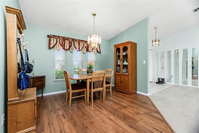 dining area featuring an inviting chandelier, lofted ceiling, and wood-type flooring