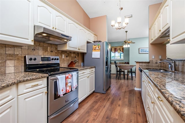 kitchen with stainless steel appliances, white cabinetry, dark stone countertops, and ceiling fan with notable chandelier