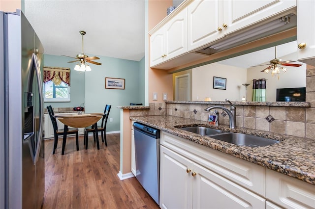 kitchen with sink, appliances with stainless steel finishes, white cabinets, dark stone counters, and dark wood-type flooring