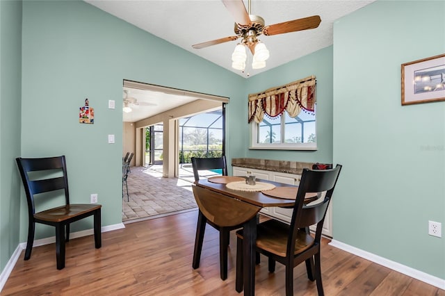 dining area with lofted ceiling, a textured ceiling, ceiling fan, and wood-type flooring