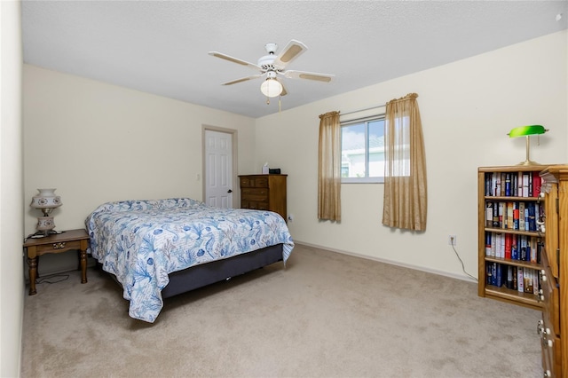 bedroom featuring ceiling fan, light carpet, and a textured ceiling