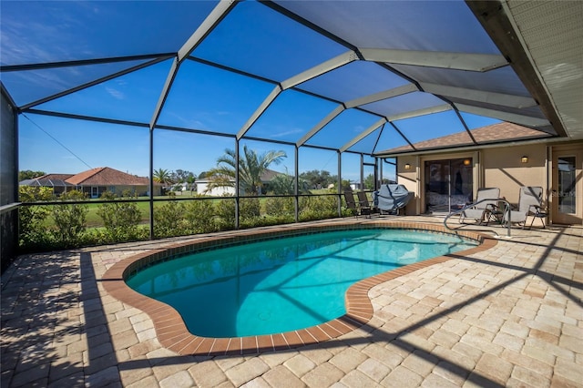 view of pool featuring a grill, glass enclosure, and a patio area