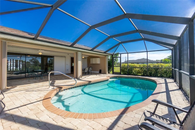 view of pool with a patio area, ceiling fan, glass enclosure, and a mountain view