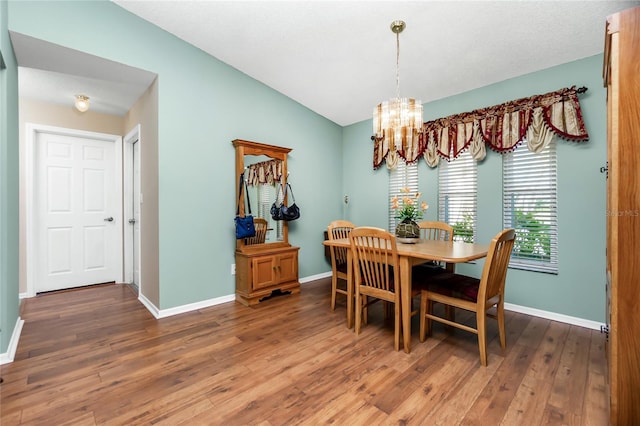 dining space with a notable chandelier, dark hardwood / wood-style floors, and lofted ceiling