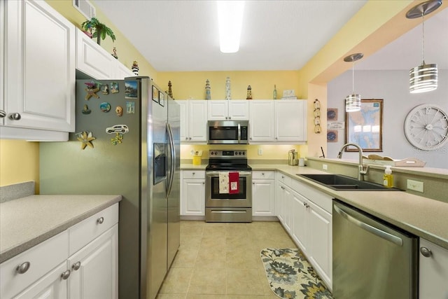 kitchen featuring stainless steel appliances, sink, light tile patterned floors, decorative light fixtures, and white cabinetry