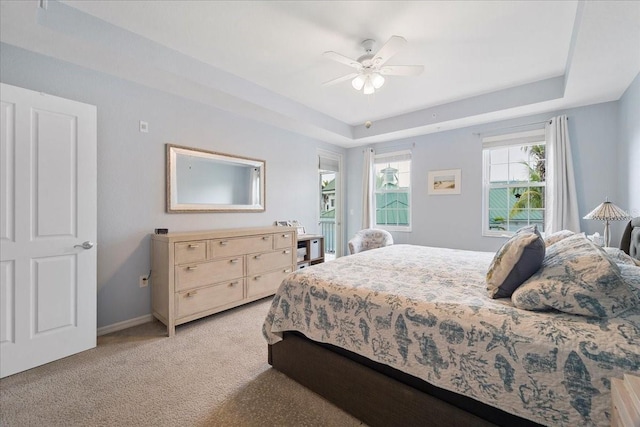 carpeted bedroom with a tray ceiling and ceiling fan