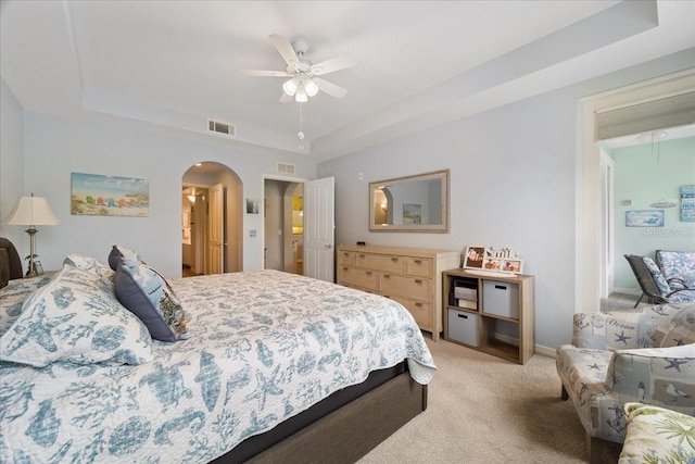 carpeted bedroom featuring a tray ceiling and ceiling fan