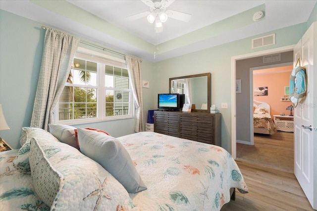 bedroom featuring a raised ceiling, ceiling fan, and hardwood / wood-style floors