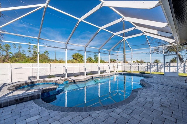 view of pool featuring an in ground hot tub, a patio area, and glass enclosure