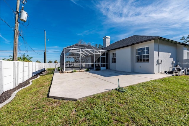 rear view of property with a lawn, a patio, and glass enclosure