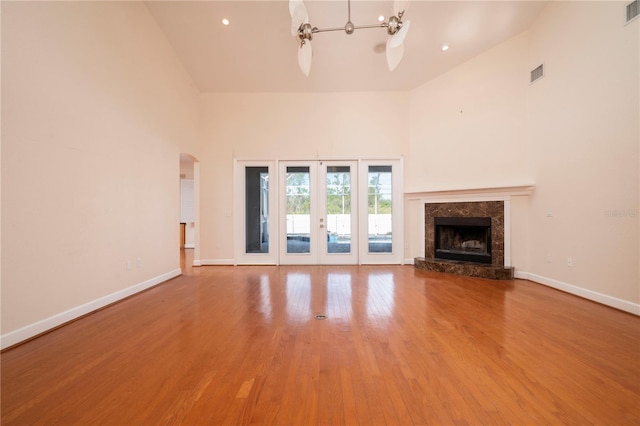 unfurnished living room with high vaulted ceiling, ceiling fan, a fireplace, and hardwood / wood-style flooring