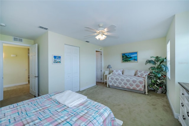 bedroom featuring light colored carpet, ceiling fan, and a closet