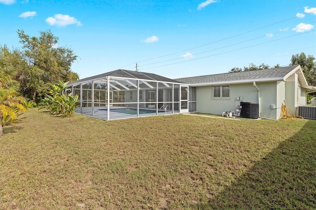 rear view of house featuring a lanai, cooling unit, and a lawn