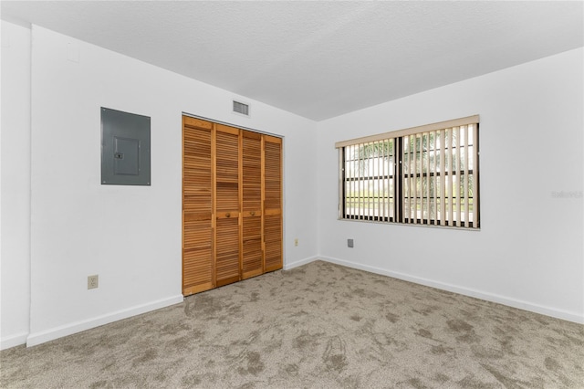 unfurnished bedroom featuring electric panel, light carpet, and a closet