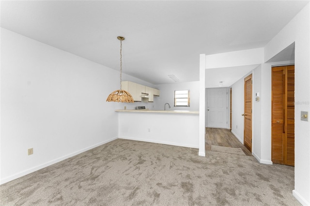 unfurnished living room featuring light colored carpet and sink