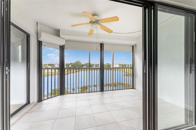 unfurnished sunroom featuring a water view and ceiling fan