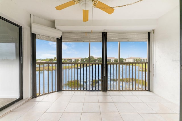 unfurnished sunroom featuring a water view, ceiling fan, and plenty of natural light