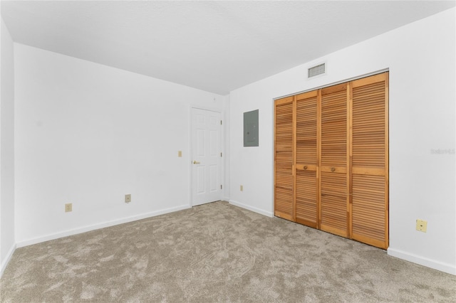 unfurnished bedroom featuring light colored carpet, electric panel, and a closet