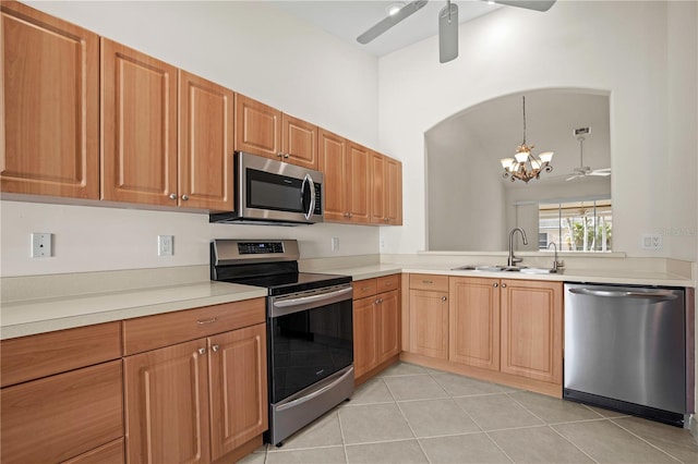 kitchen featuring sink, light tile patterned flooring, stainless steel appliances, and ceiling fan with notable chandelier