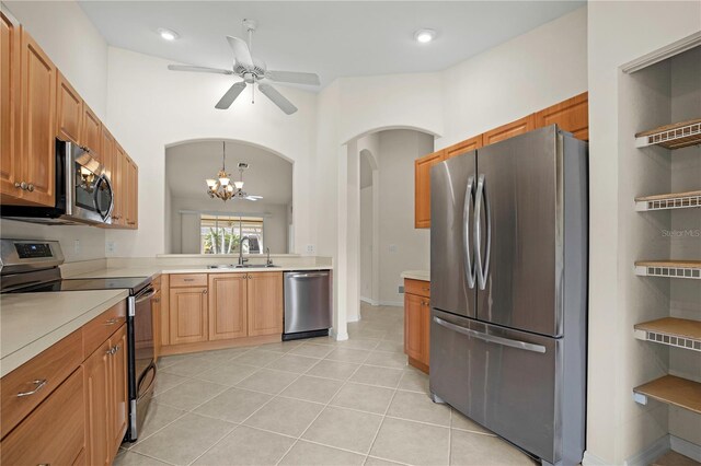 kitchen featuring pendant lighting, ceiling fan with notable chandelier, sink, light tile patterned floors, and appliances with stainless steel finishes