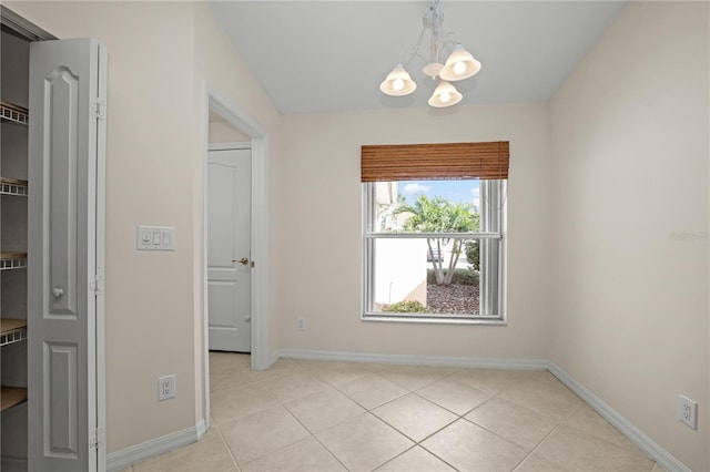 empty room with a notable chandelier and light tile patterned flooring