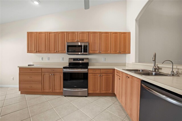 kitchen with high vaulted ceiling, sink, light tile patterned floors, appliances with stainless steel finishes, and kitchen peninsula