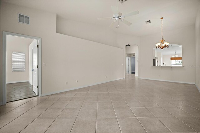 unfurnished living room with light tile patterned floors and ceiling fan with notable chandelier