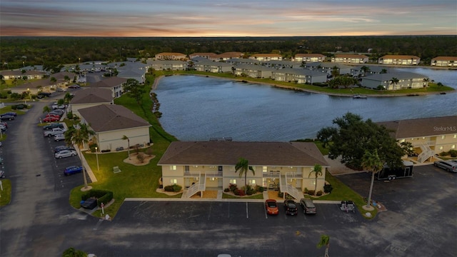 aerial view at dusk with a water view and a residential view