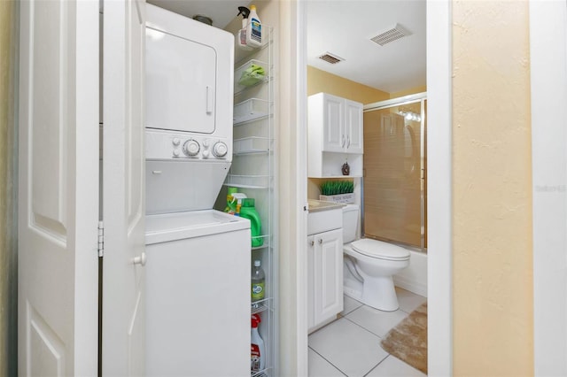 bathroom with vanity, toilet, stacked washer / drying machine, and tile patterned flooring