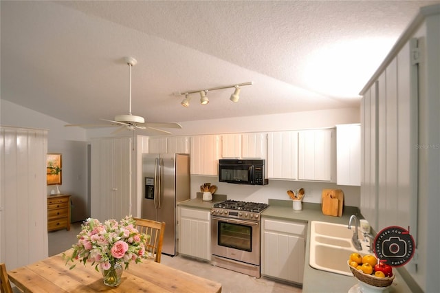 kitchen featuring sink, vaulted ceiling, a textured ceiling, appliances with stainless steel finishes, and ceiling fan