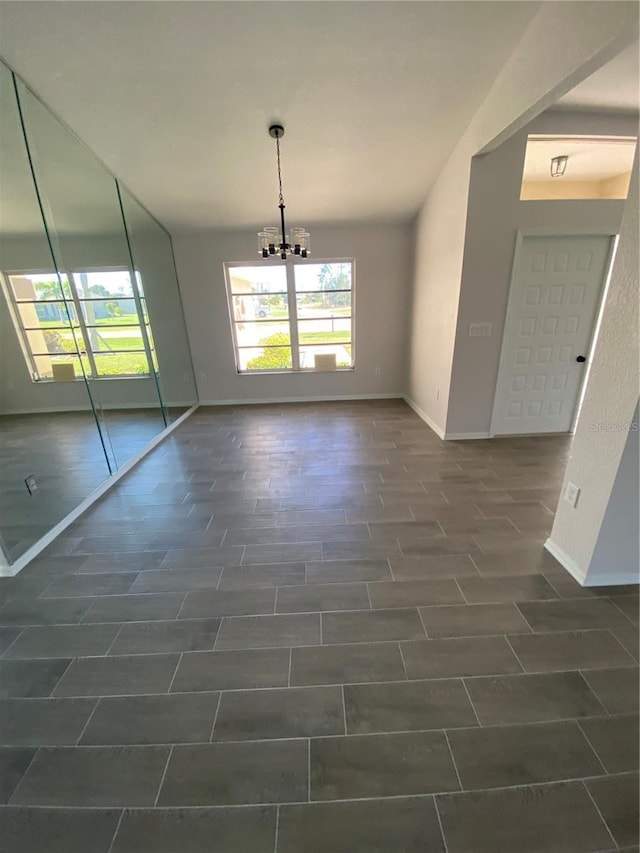 unfurnished dining area with baseboards and an inviting chandelier