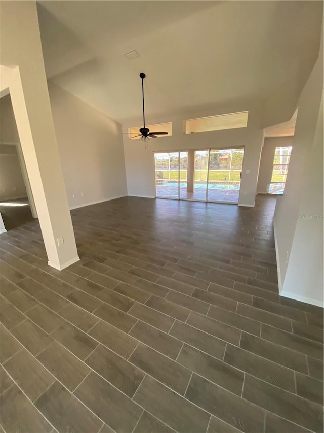 interior space featuring a ceiling fan, a wealth of natural light, dark wood-type flooring, and baseboards