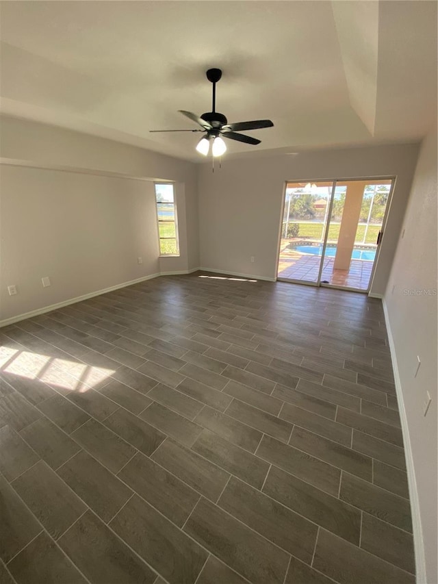 unfurnished room featuring a ceiling fan, baseboards, and dark wood-style flooring