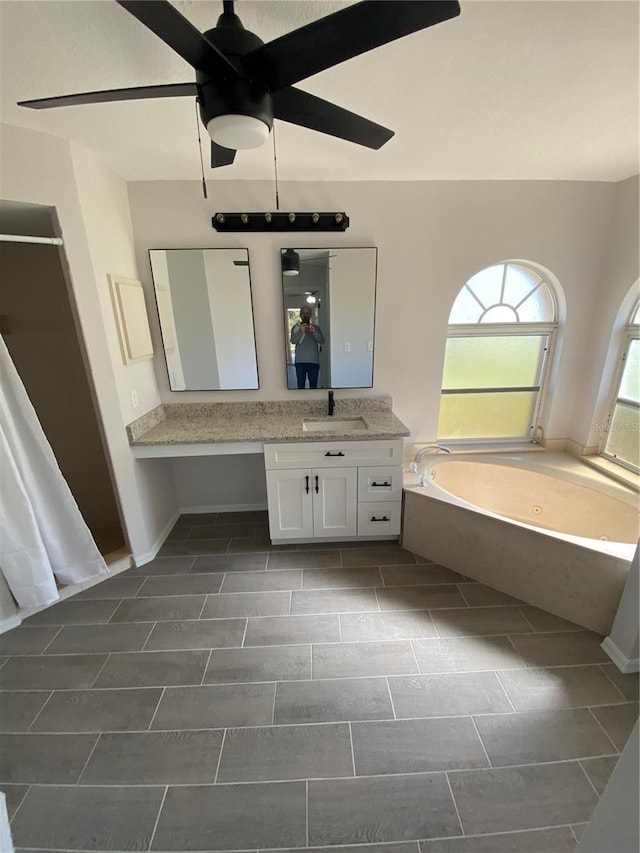 full bathroom featuring a garden tub, vanity, and a ceiling fan