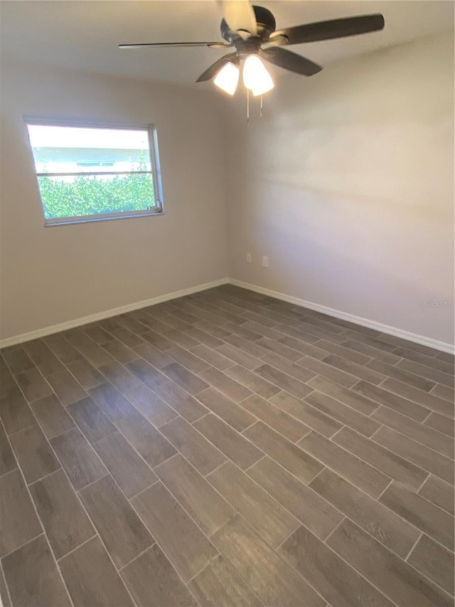 empty room with dark wood-style floors, ceiling fan, and baseboards