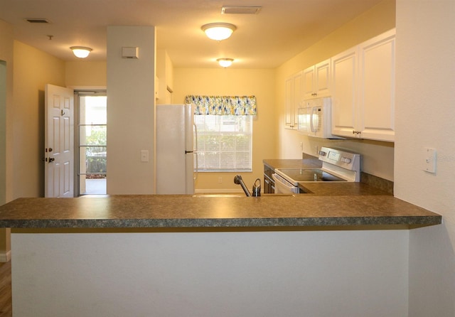 kitchen with kitchen peninsula, white cabinetry, sink, and white appliances