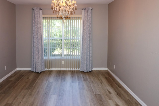 spare room featuring a chandelier and hardwood / wood-style flooring