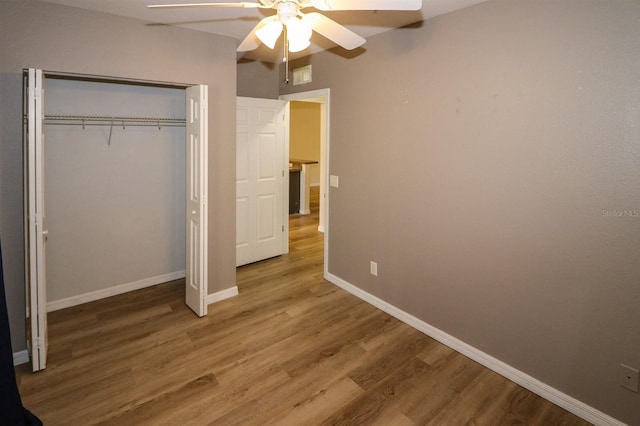 unfurnished bedroom with ceiling fan, wood-type flooring, and a closet