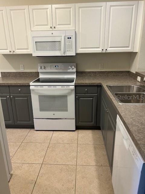 kitchen with white cabinetry, light tile patterned flooring, white appliances, and sink