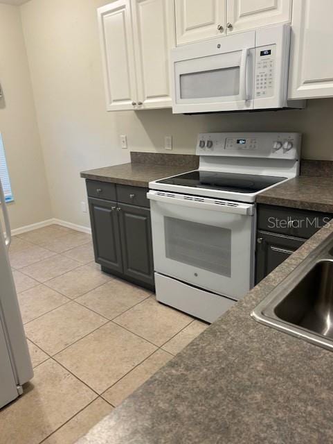 kitchen with white appliances, white cabinetry, sink, and light tile patterned floors