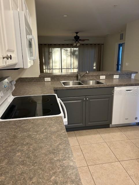 kitchen featuring white cabinetry, ceiling fan, sink, white appliances, and light tile patterned floors