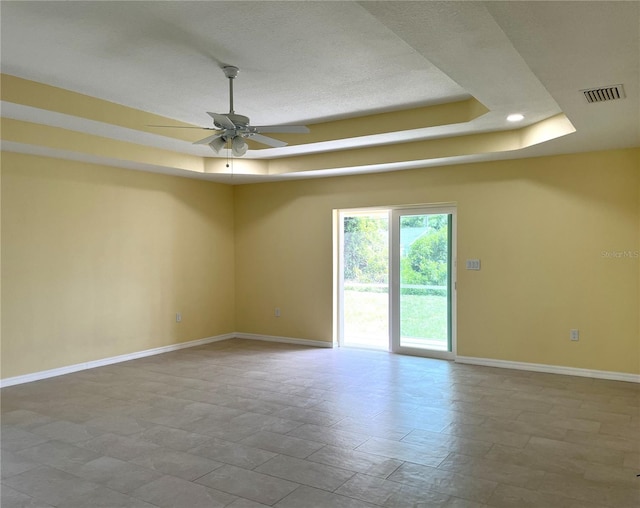 unfurnished room with ceiling fan and a tray ceiling