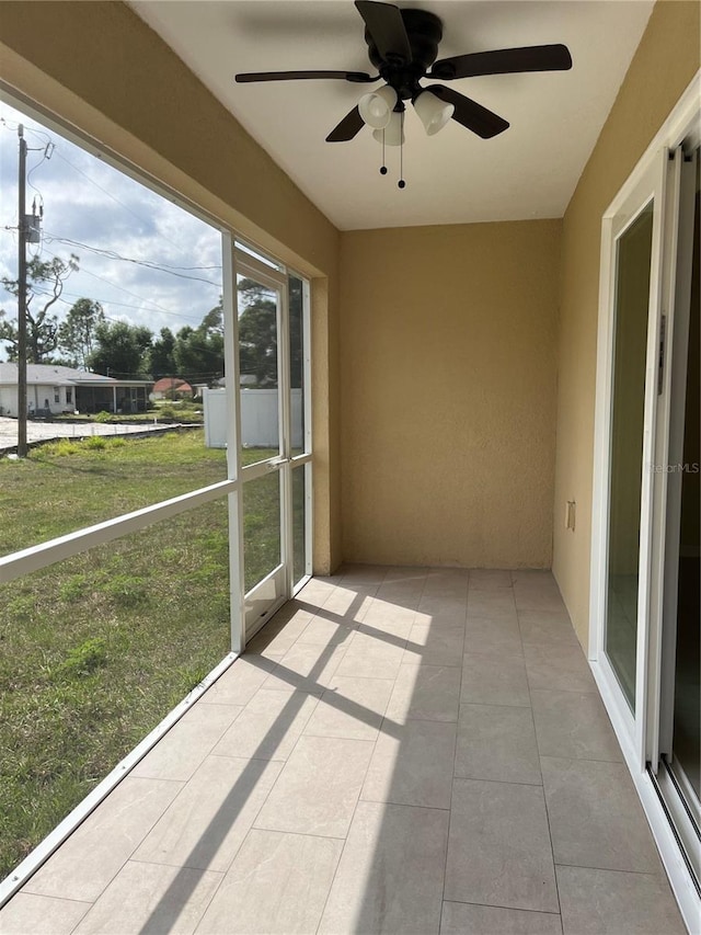 unfurnished sunroom with ceiling fan