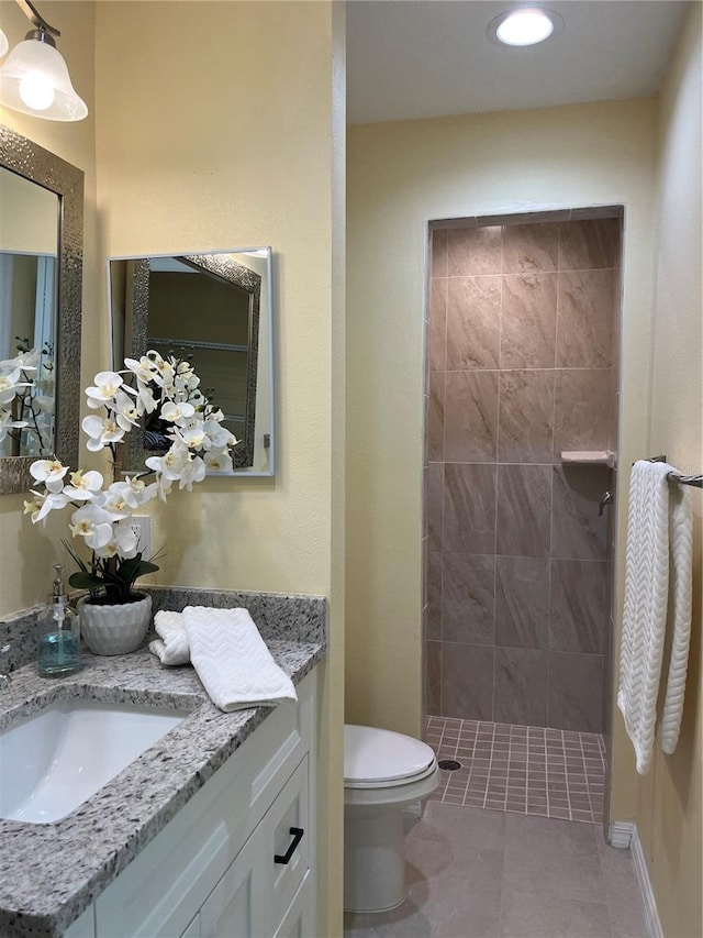 bathroom featuring vanity, tile patterned flooring, toilet, and tiled shower