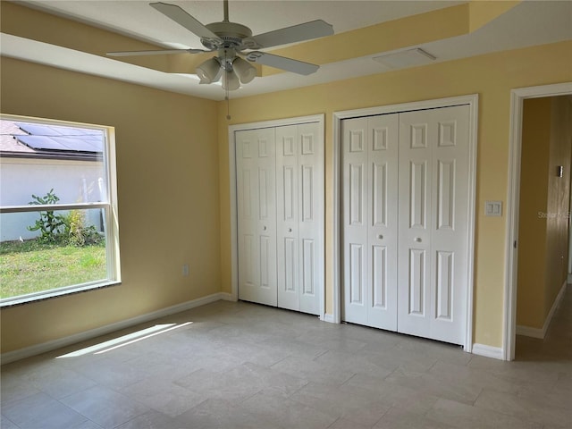 unfurnished bedroom featuring multiple closets and ceiling fan