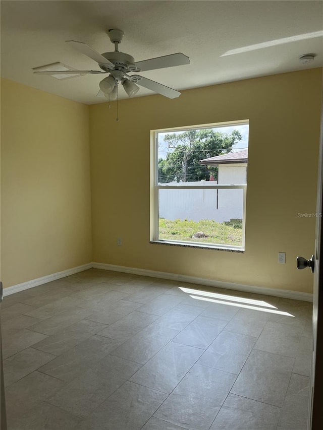 spare room with ceiling fan and light tile patterned floors